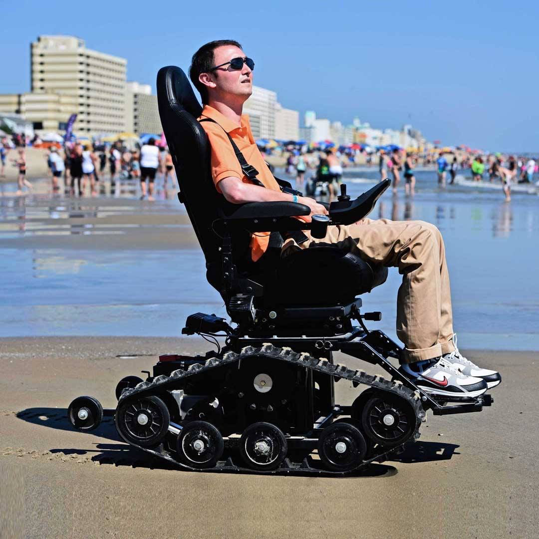 A TracFab rider on the sand beside a busy beach.