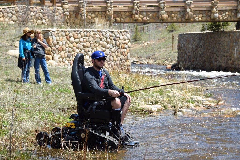 A rider fishing from a TracFab at the edge of a stream.