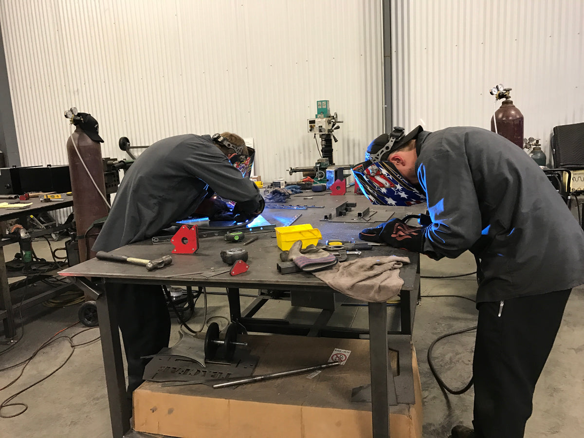 Two TracFab team members welding components at a fabrication table in the Pennsylvania shop.