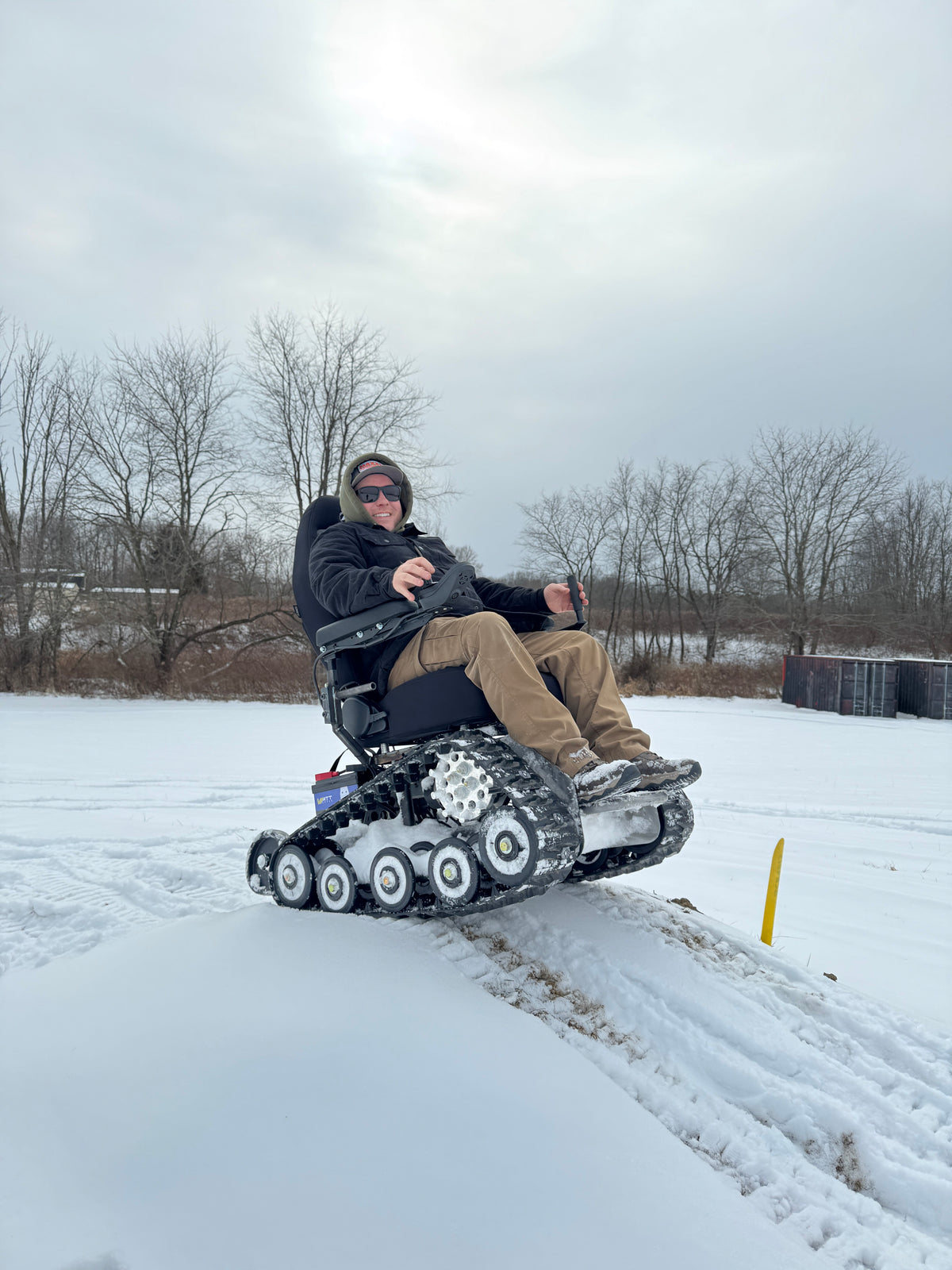 A TracFab rider crossing snow-covered ground with tracks visible in the snow.